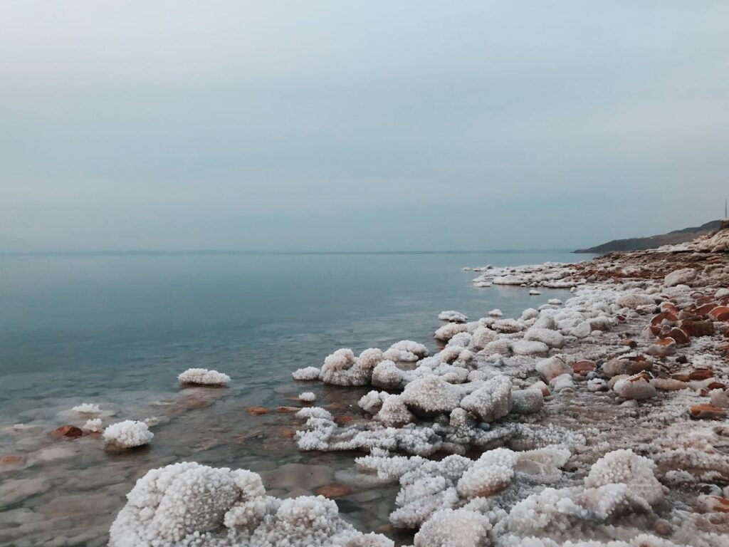 Crystalline salt formations on seashore under overcast sky
